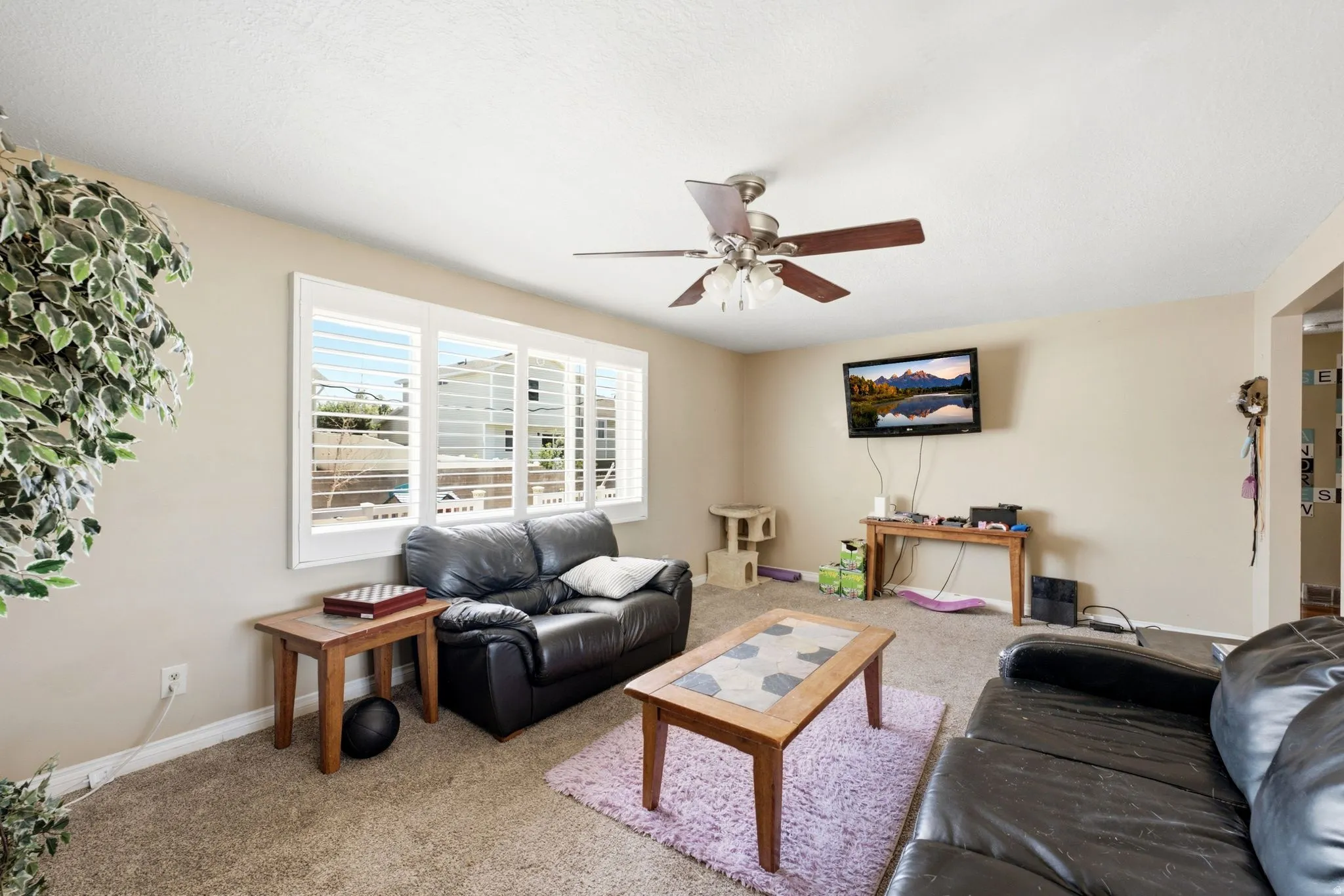 Living area featuring carpet flooring, neutral paint tones, and a ceiling fan with light fixture