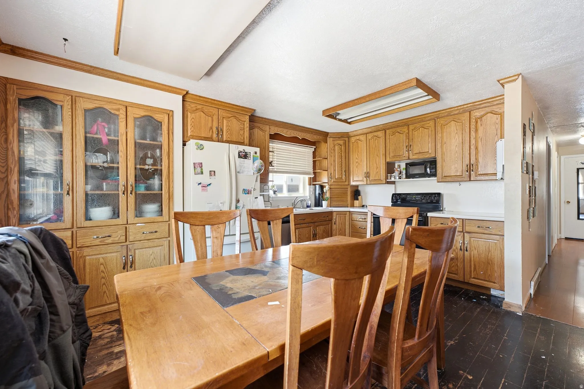 Kitchen featuring extensive wood cabinetry, a built-in display hutch with glass-front doors, white appliances, and contrasting dark flooring