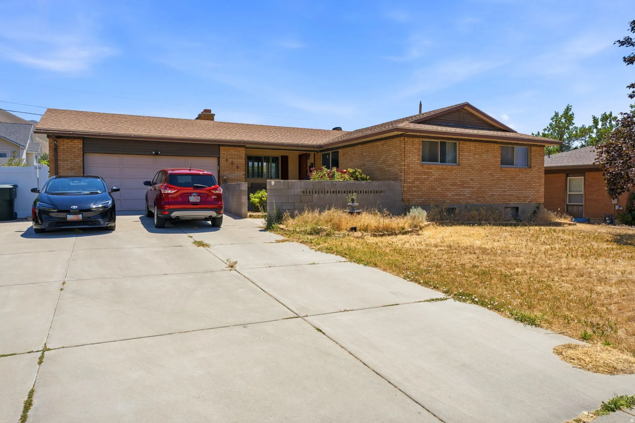Brick facade exterior with a two-car garage, concrete driveway, and covered entry