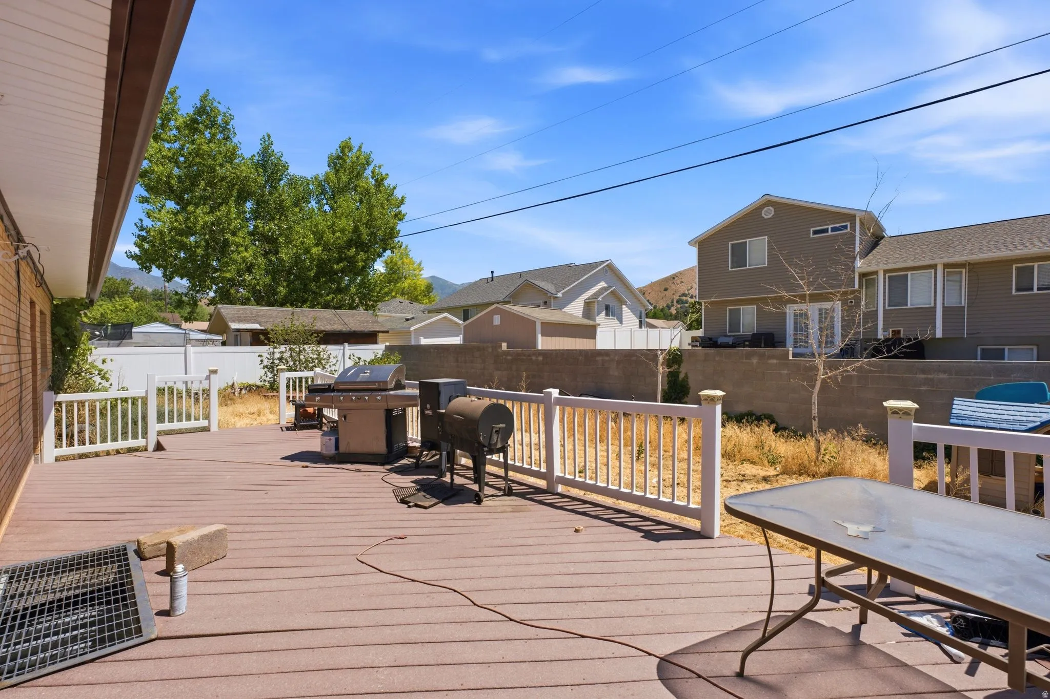 Expansive outdoor deck featuring composite decking, white railing, and a brick exterior wall