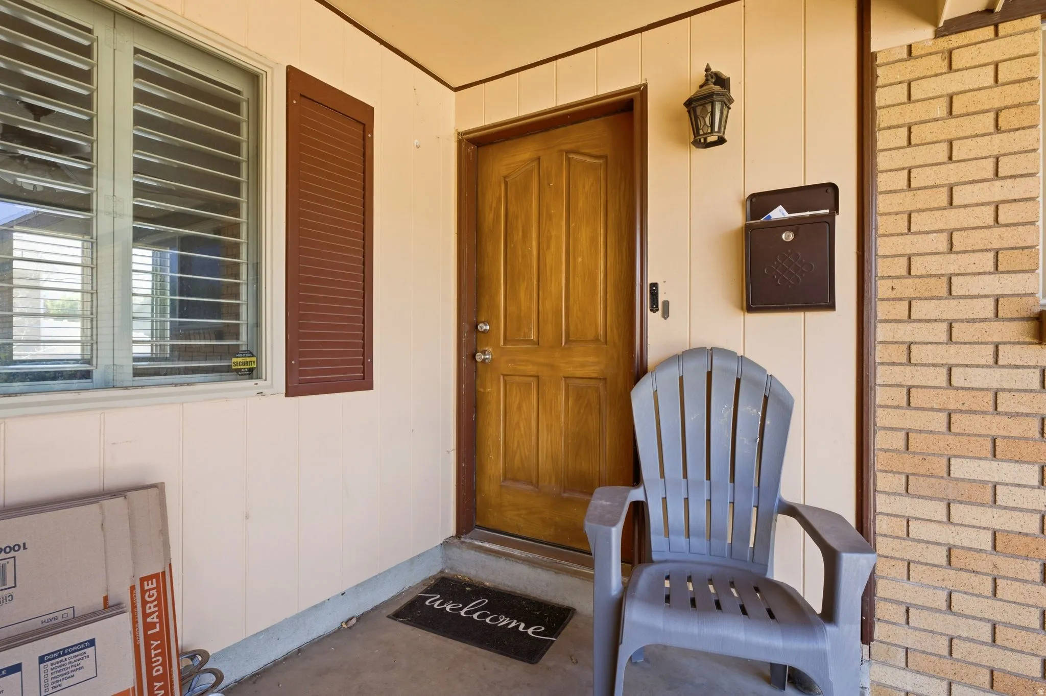 Inviting entryway featuring a paneled wood door, exterior wall lantern, and a decorative mailbox