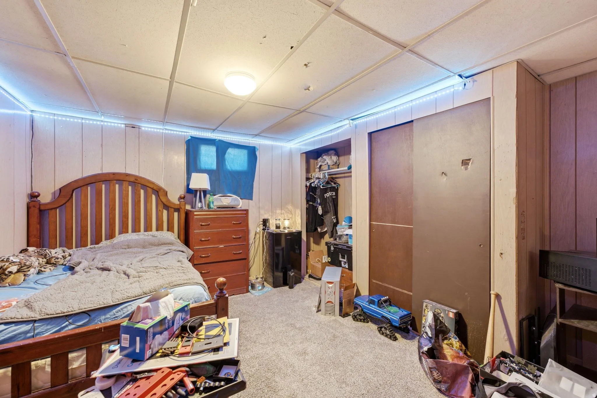 Carpeted room with a drop ceiling and two-tone wall paneling
