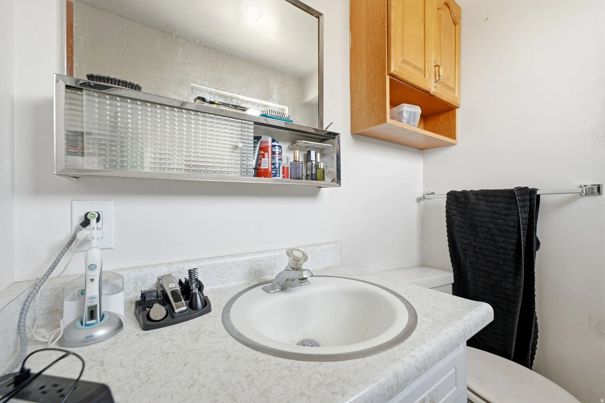 Bathroom vanity featuring a white drop-in sink, laminate countertop, and overhead medicine cabinet with frosted sliding doors