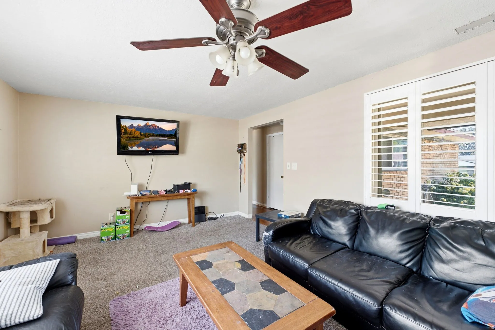 Living area featuring neutral wall paint, a ceiling fan with integrated lighting, and carpet flooring