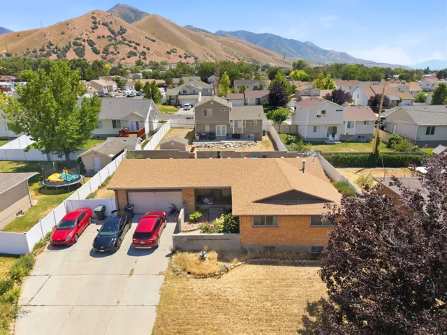 Brick exterior with an attached garage, featuring a concrete driveway, sloped roofline, and a prominent mountain backdrop