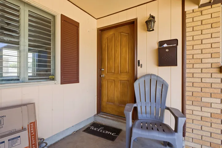 Inviting entryway featuring a paneled wood door, exterior wall lantern, and a decorative mailbox