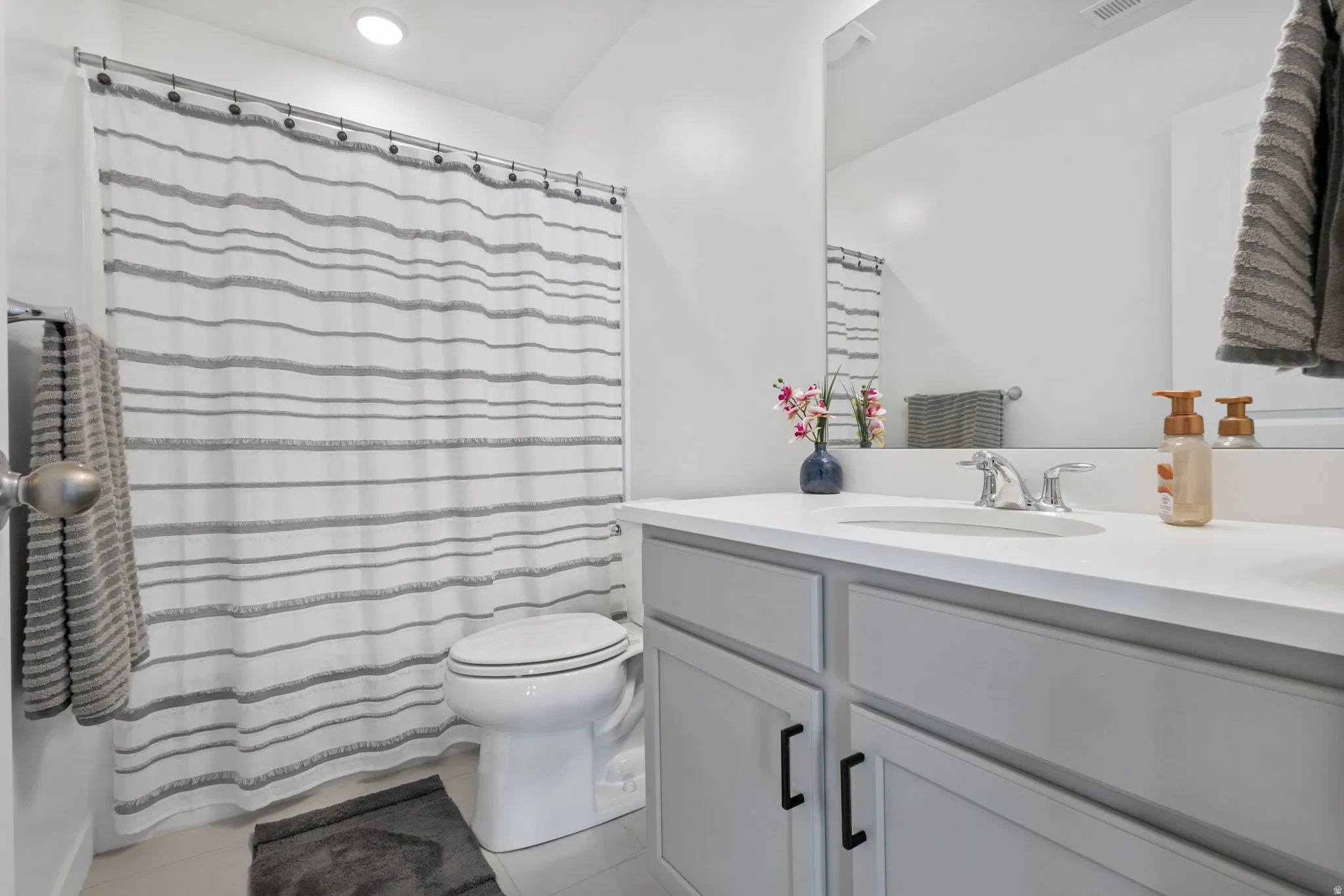Bathroom featuring a white toilet, recessed lighting, and a vanity with a white countertop and gray cabinetry