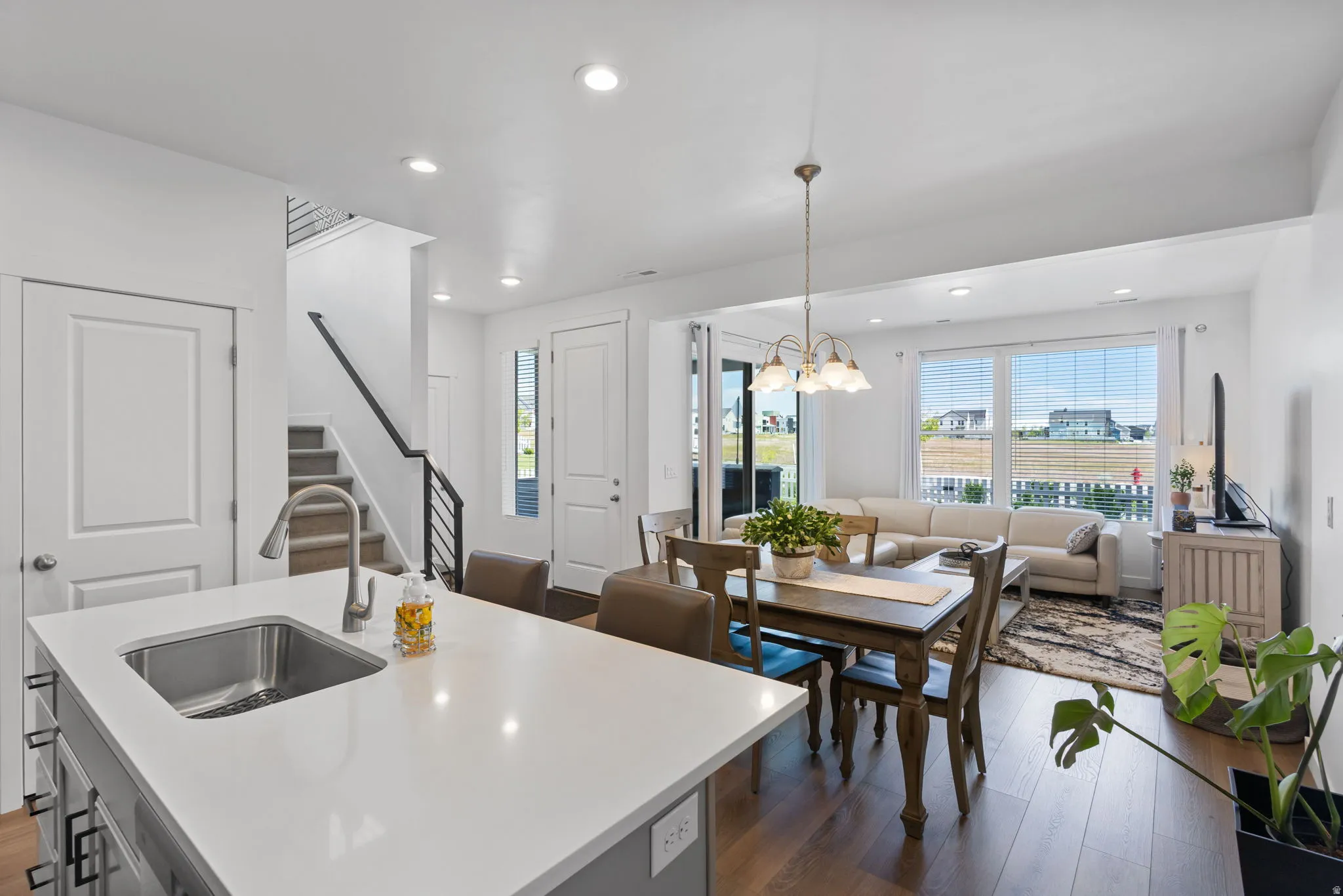 Open-concept living space featuring wood-finish flooring, recessed lighting, and a kitchen island with an undermount sink