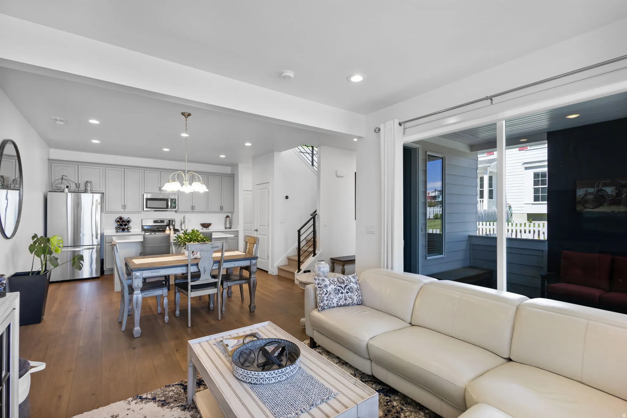 Open-concept living area featuring wood-finish flooring, recessed lighting, and a sliding glass door leading to an outdoor patio