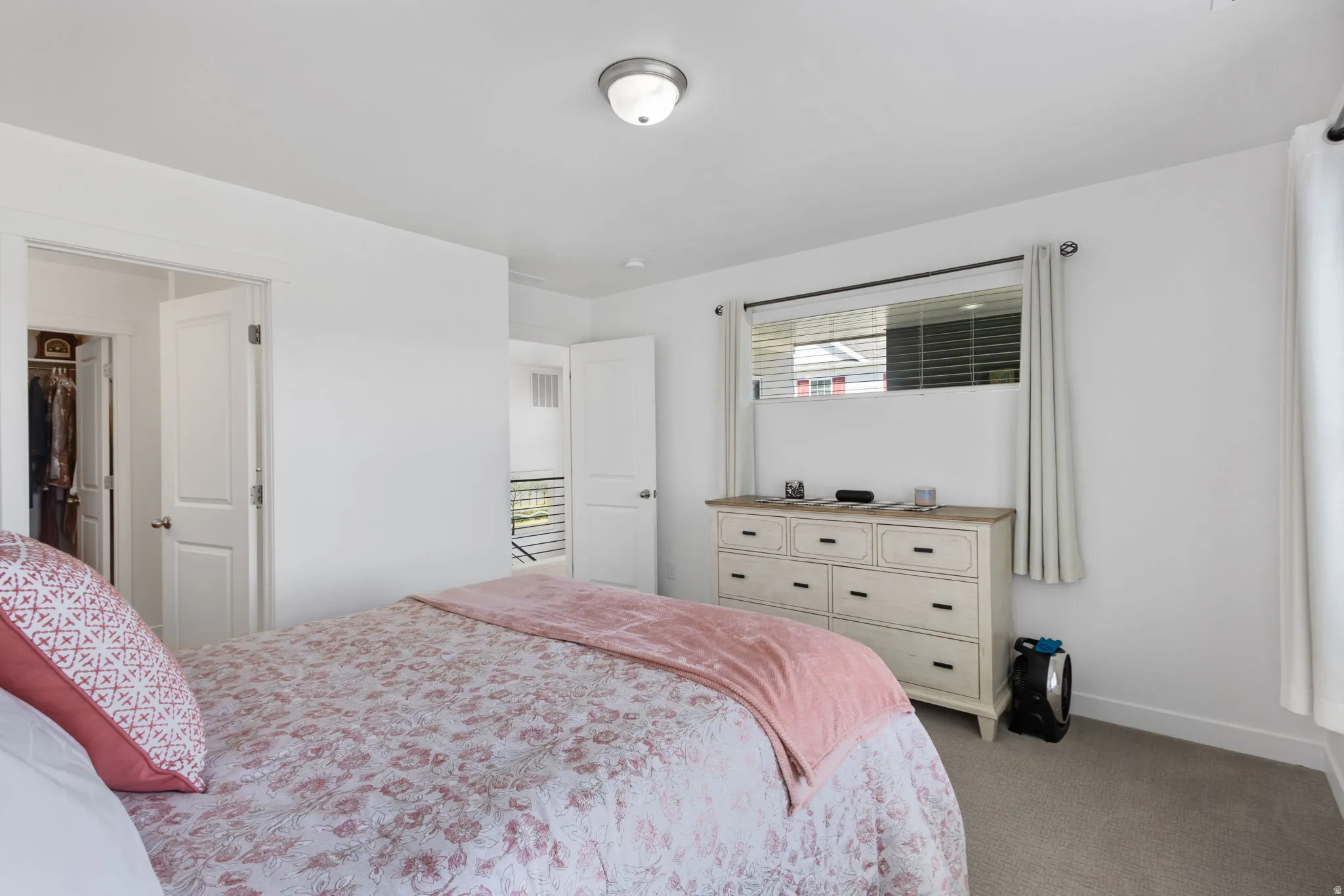 Carpeted bedroom featuring white walls, a single window with blinds, and a flush mount ceiling light