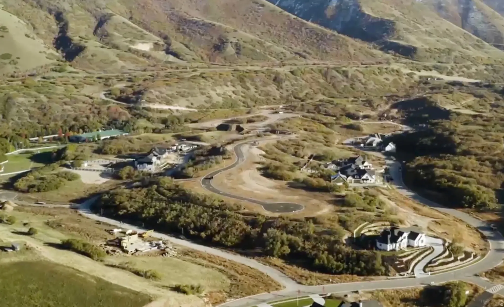 Expansive aerial showcasing multiple new construction homes and vacant lots nestled within a mountainous landscape