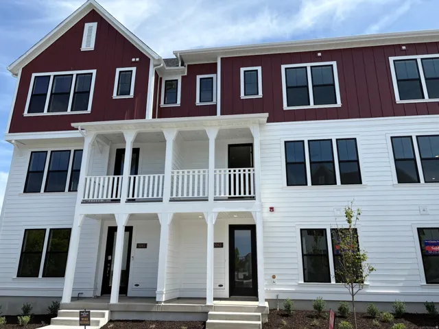 Multi-level exterior featuring white siding and dark red board-and-batten accents