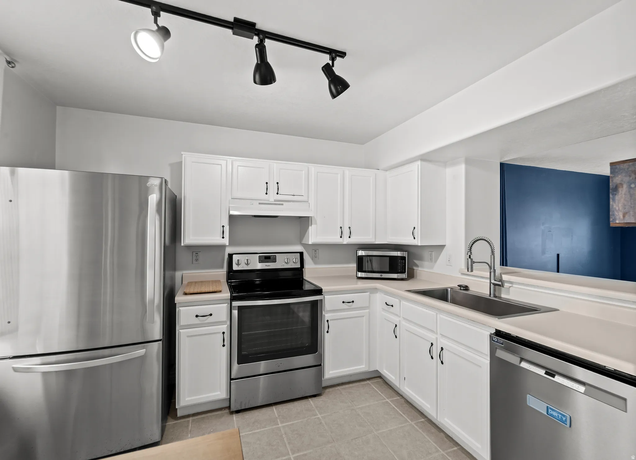 Kitchen featuring white cabinetry, light-toned countertops, and stainless steel appliances