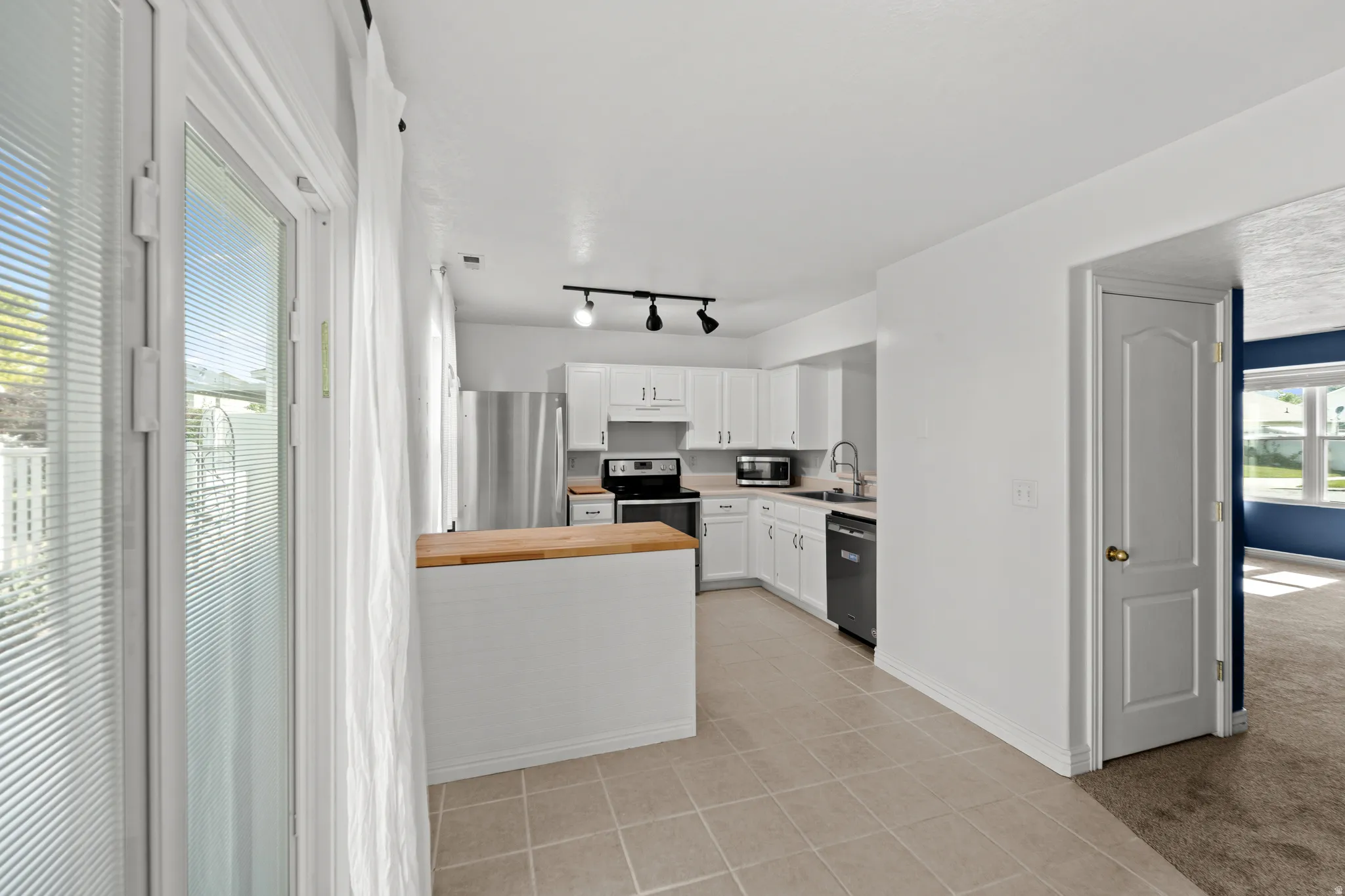 Contemporary kitchen featuring white cabinetry and light wood-finish countertops