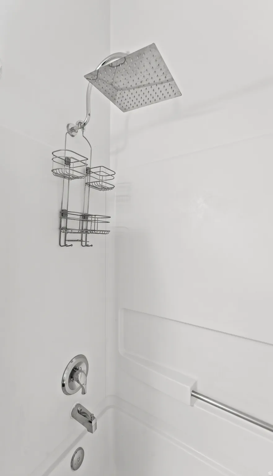 White bath and shower combination featuring a square rainfall showerhead