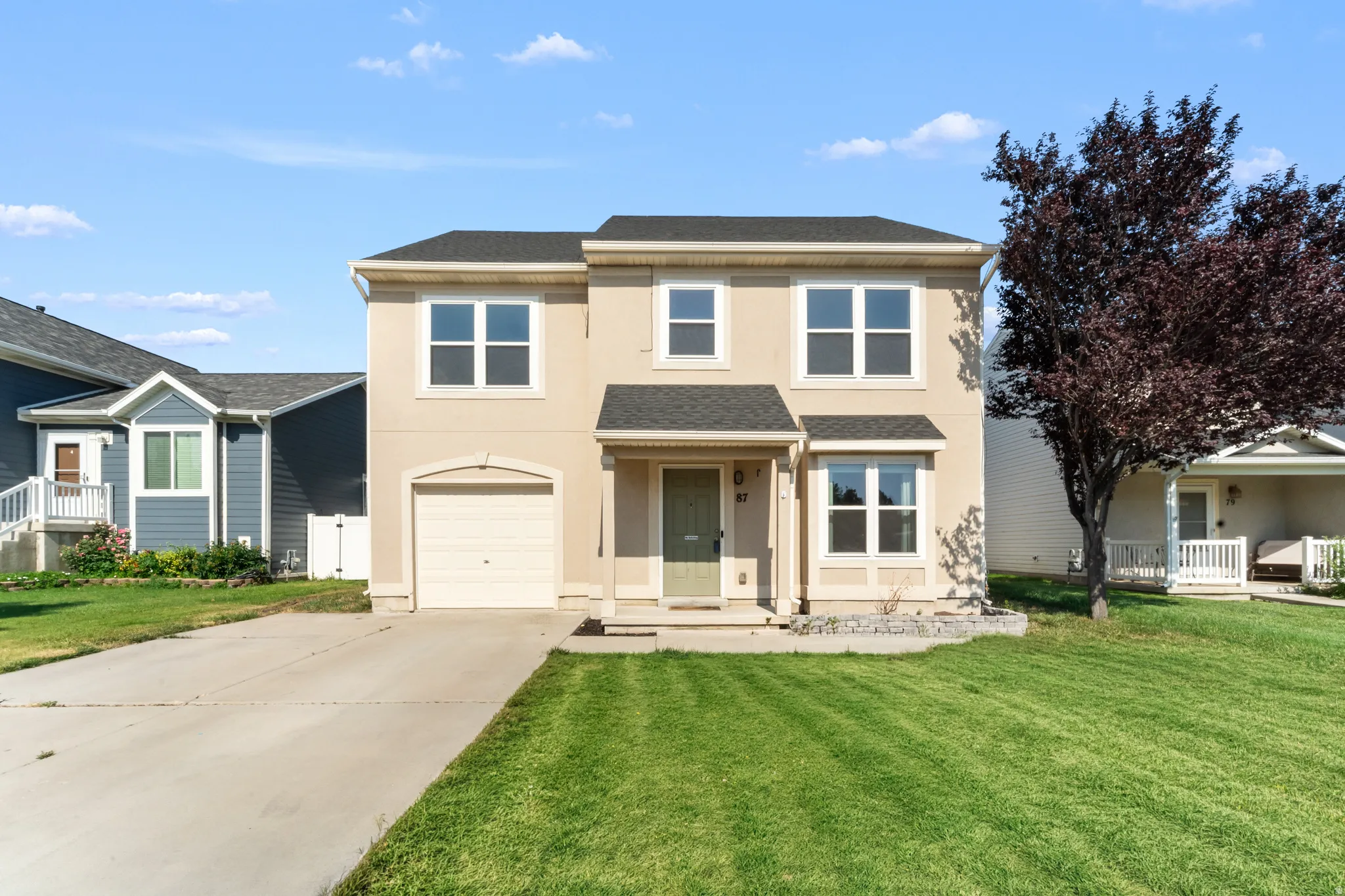 Two-story exterior with a neutral stucco finish, an attached single-car garage, and a covered entryway