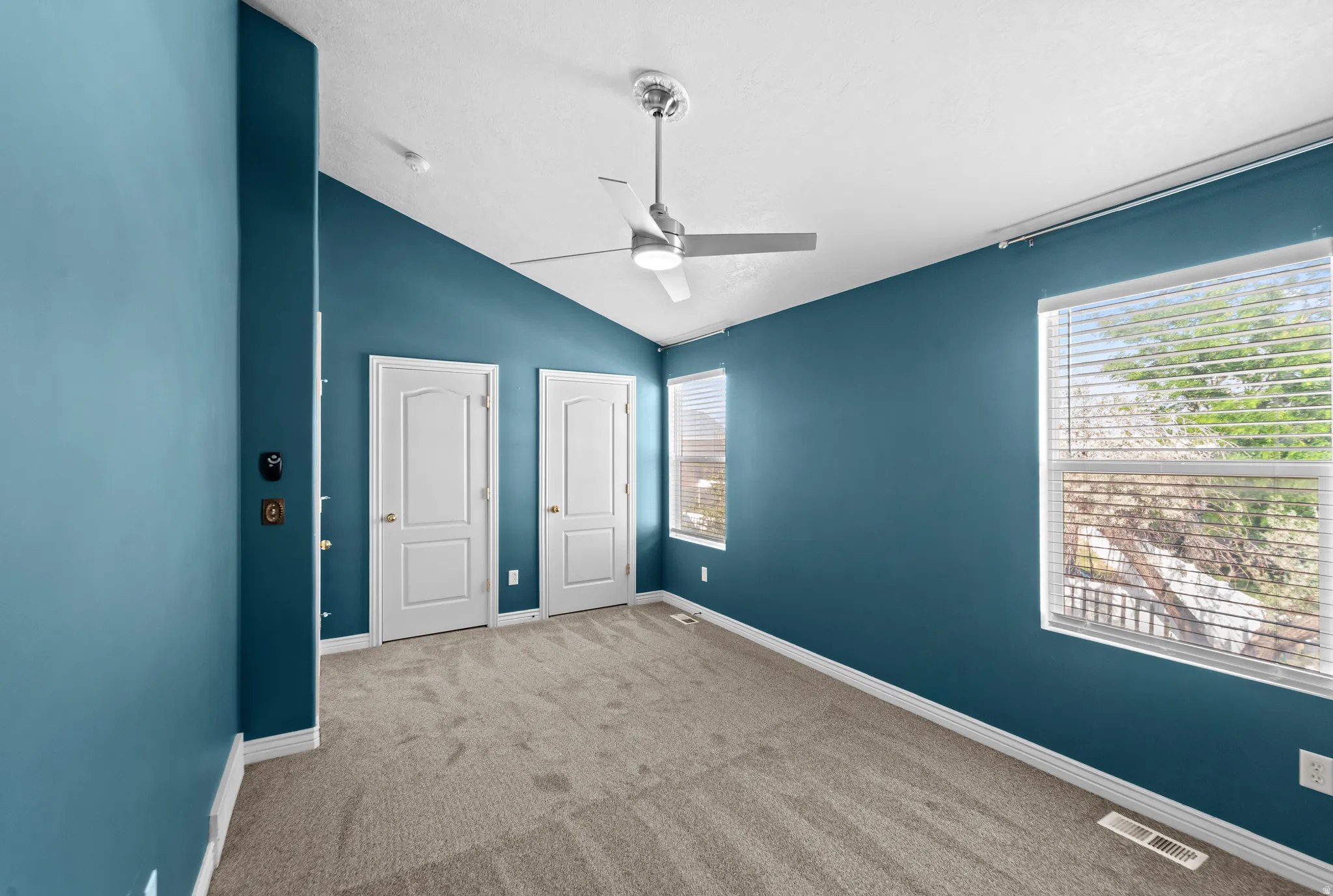 Spacious room featuring vaulted ceilings and a ceiling fan with integrated lighting