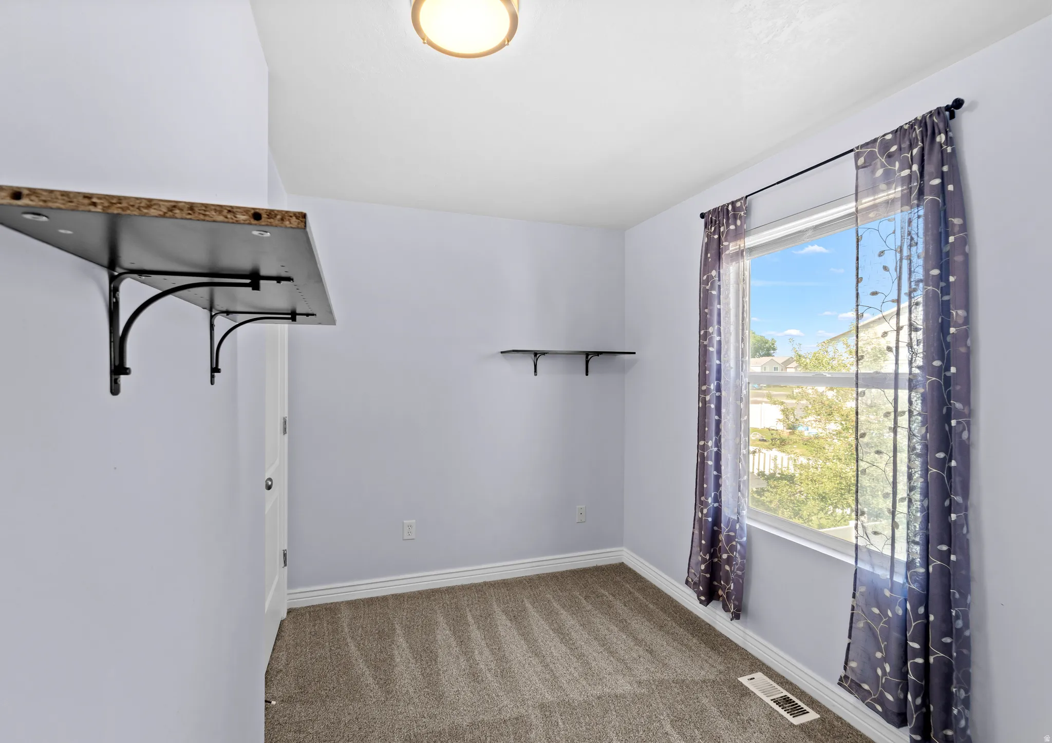 Carpeted room with light purple walls and white baseboards