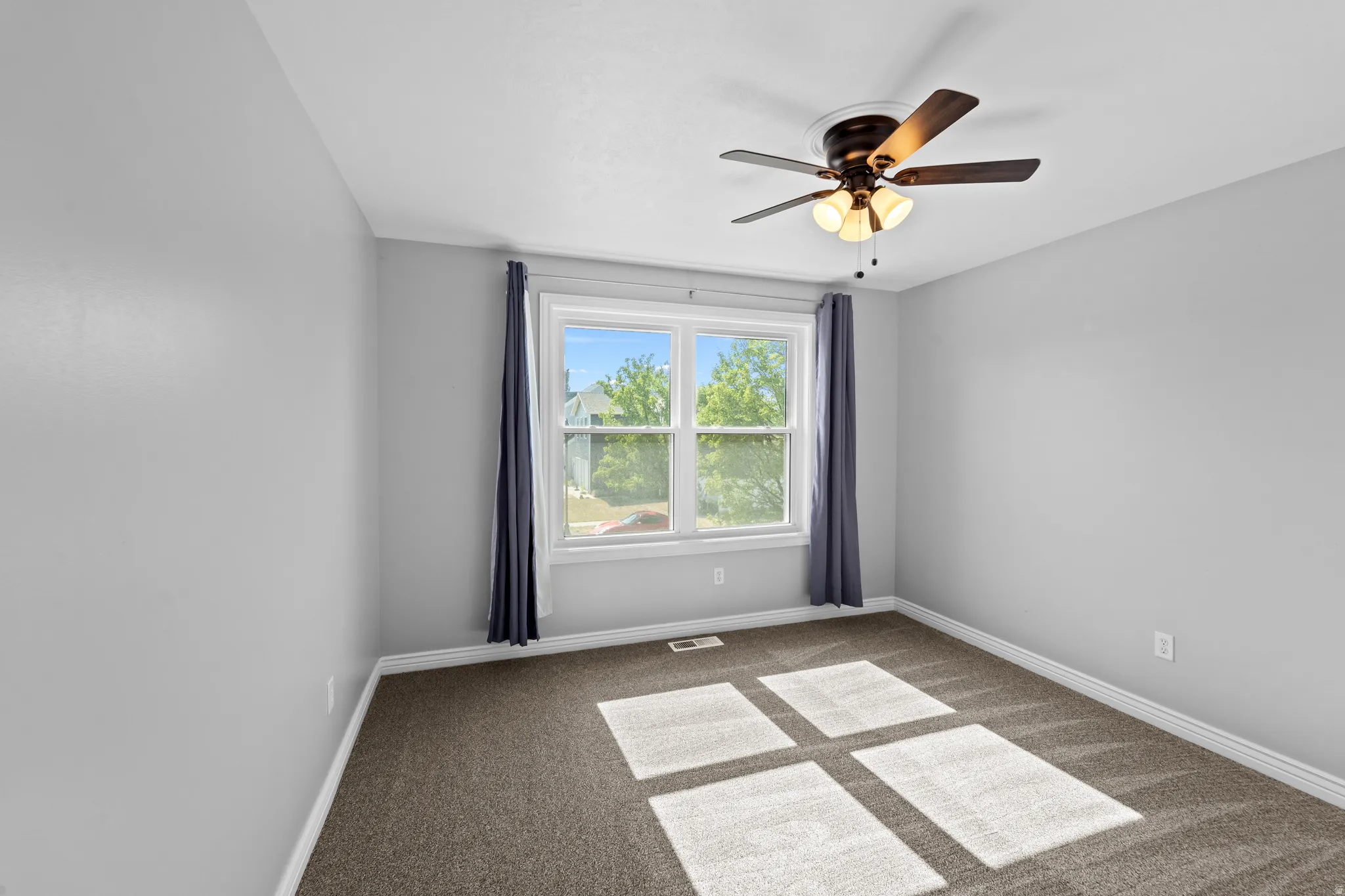 Room featuring light gray walls, brown carpet flooring, and a white trim baseboard