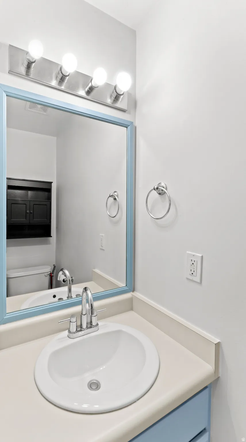 Bathroom vanity featuring an oval undermount sink, dual-handle chrome faucet, and a light-toned countertop