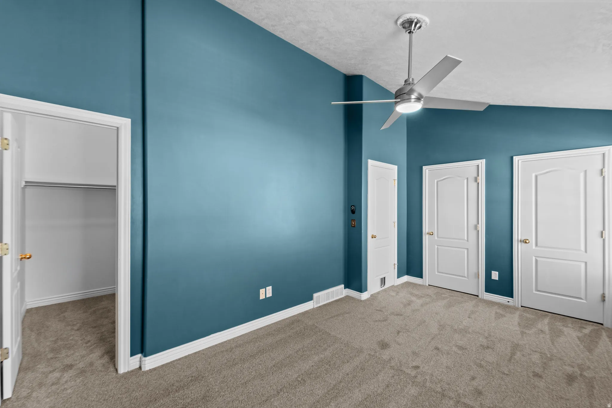 Room featuring a modern ceiling fan with integrated lighting, a spacious closet with wire shelving, and soft carpet flooring