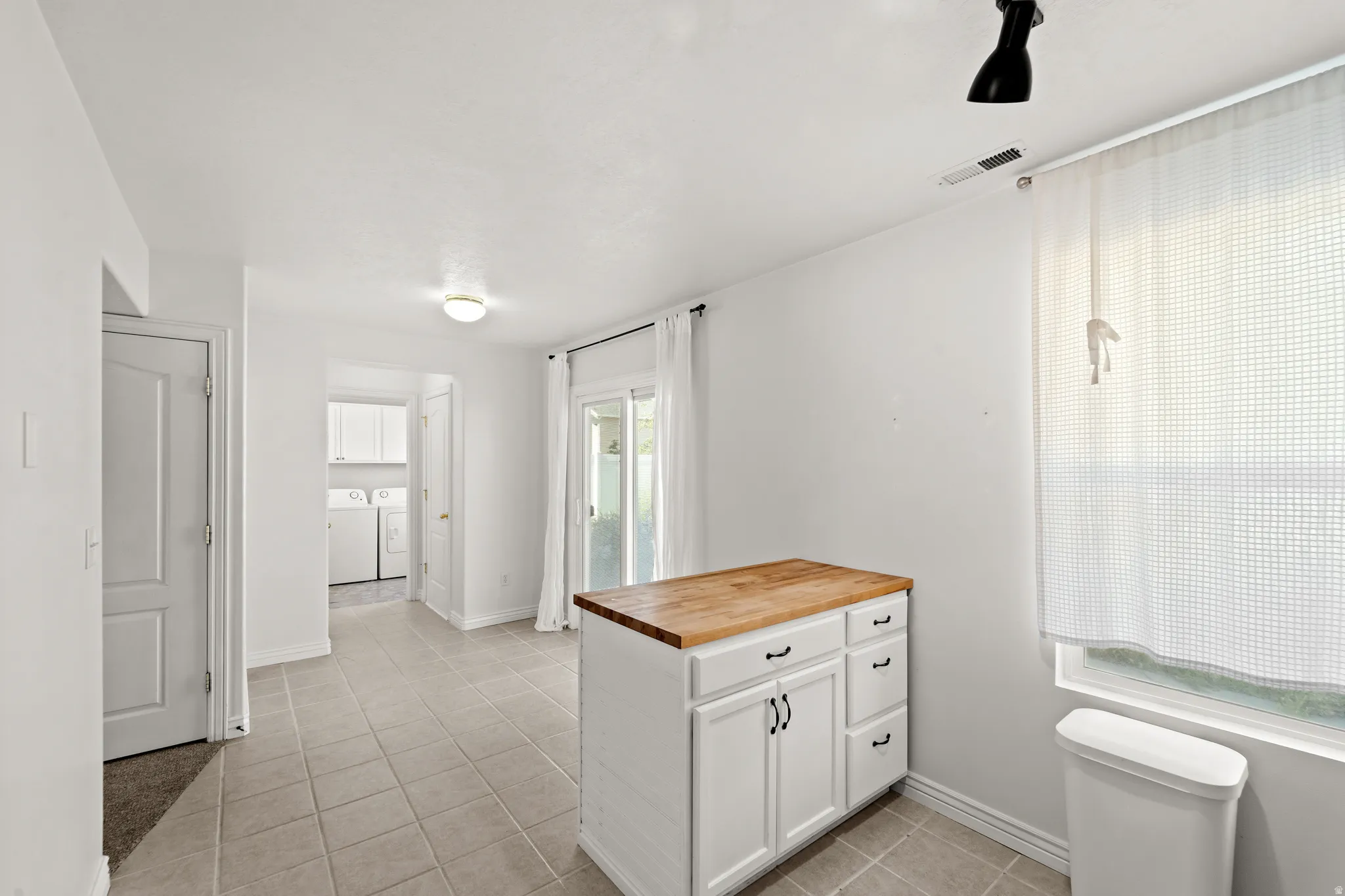 Kitchen island with a butcher block countertop and white cabinetry