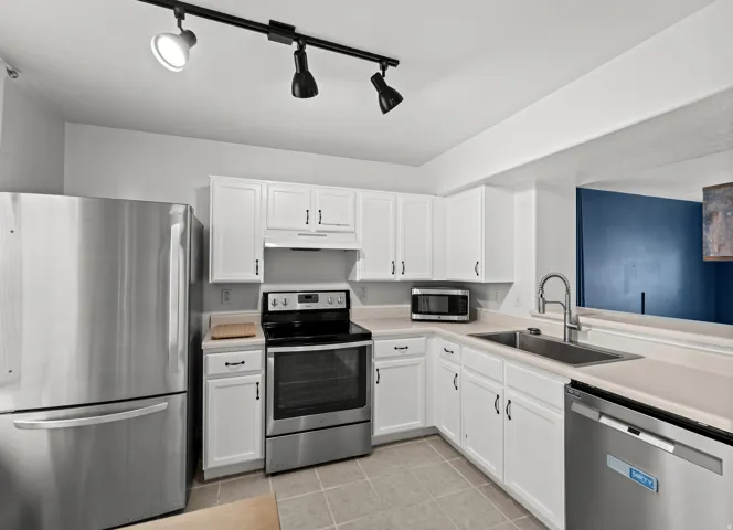 Kitchen featuring white cabinetry, light-toned countertops, and stainless steel appliances