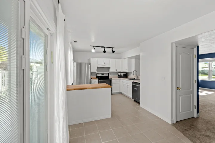 Contemporary kitchen featuring white cabinetry and light wood-finish countertops