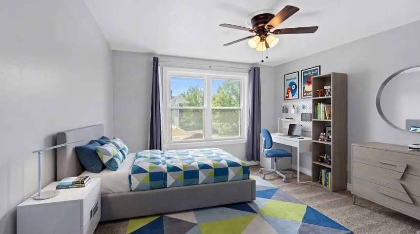 Bright interior room featuring light gray walls, a window with exterior views, and a ceiling fan with integrated lighting