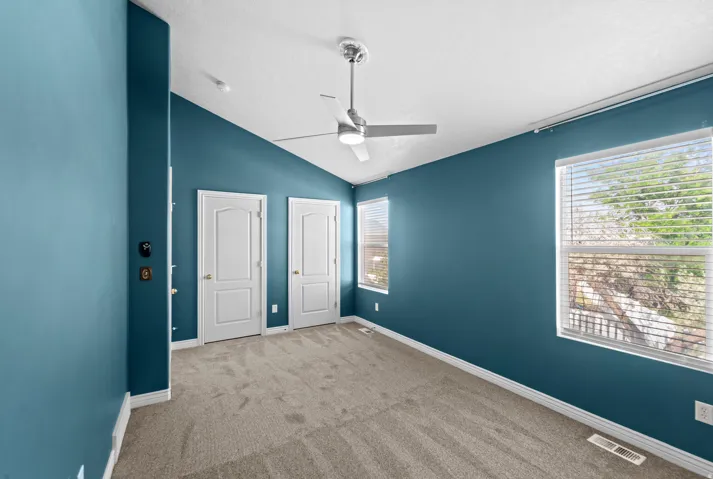 Spacious room featuring vaulted ceilings and a ceiling fan with integrated lighting