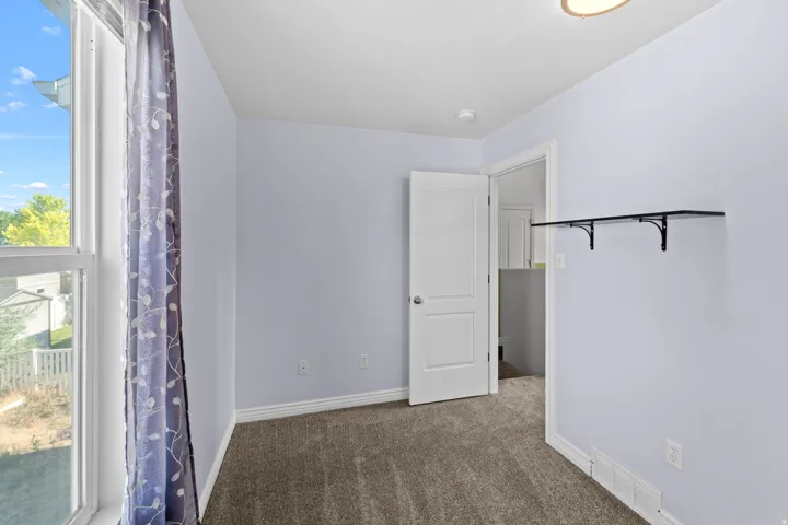 Bright room with a large window, neutral carpeting, and light-colored walls