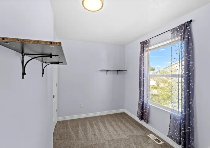 Carpeted room with light purple walls and white baseboards