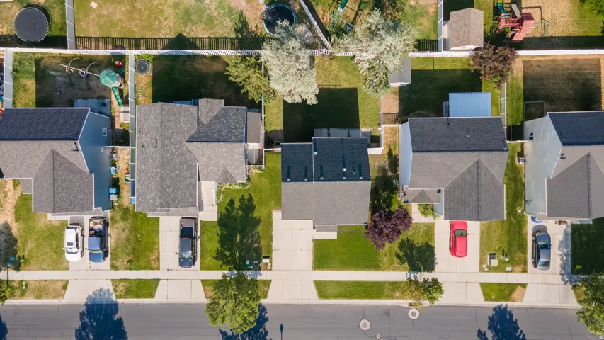 Aerial view showcasing multiple residential properties with pitched roofs, front driveways, and green lawns