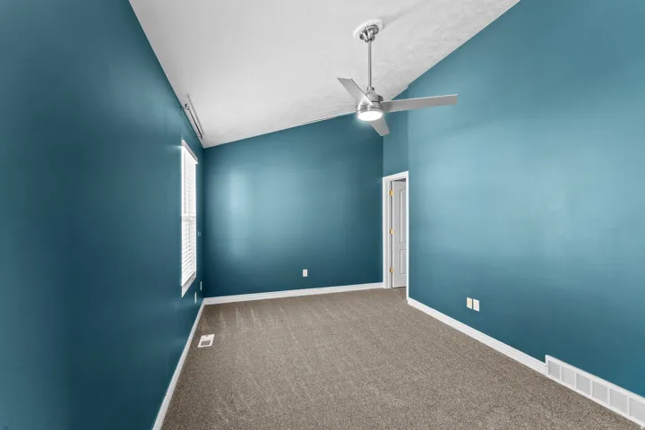 Room featuring a vaulted ceiling with a modern ceiling fan, carpeted flooring, a window with blinds, and white trim molding