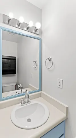 Bathroom vanity featuring an oval undermount sink, dual-handle chrome faucet, and a light-toned countertop