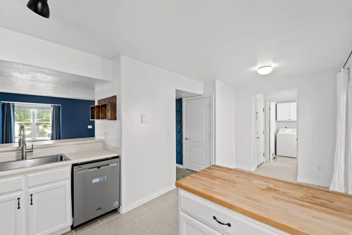 Kitchen featuring white cabinetry with dark hardware, a stainless steel sink with a high-arc faucet, and light-toned countertops