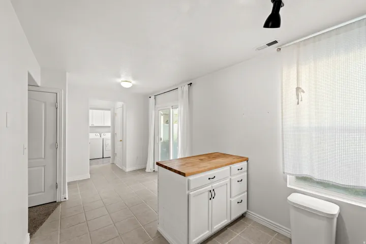 Kitchen island with a butcher block countertop and white cabinetry