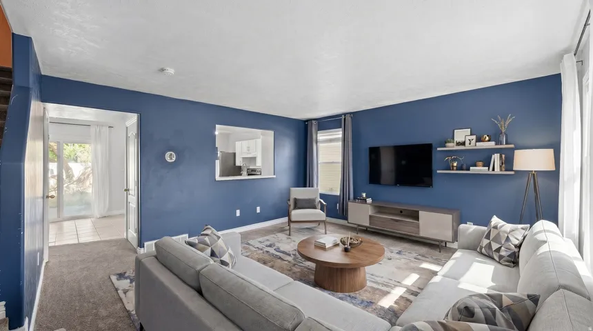 Spacious living area featuring rich blue walls, recessed lighting, and a pass-through window to the kitchen