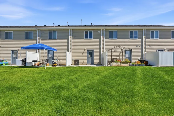 Expansive green lawn with rear building elevation featuring beige horizontal siding