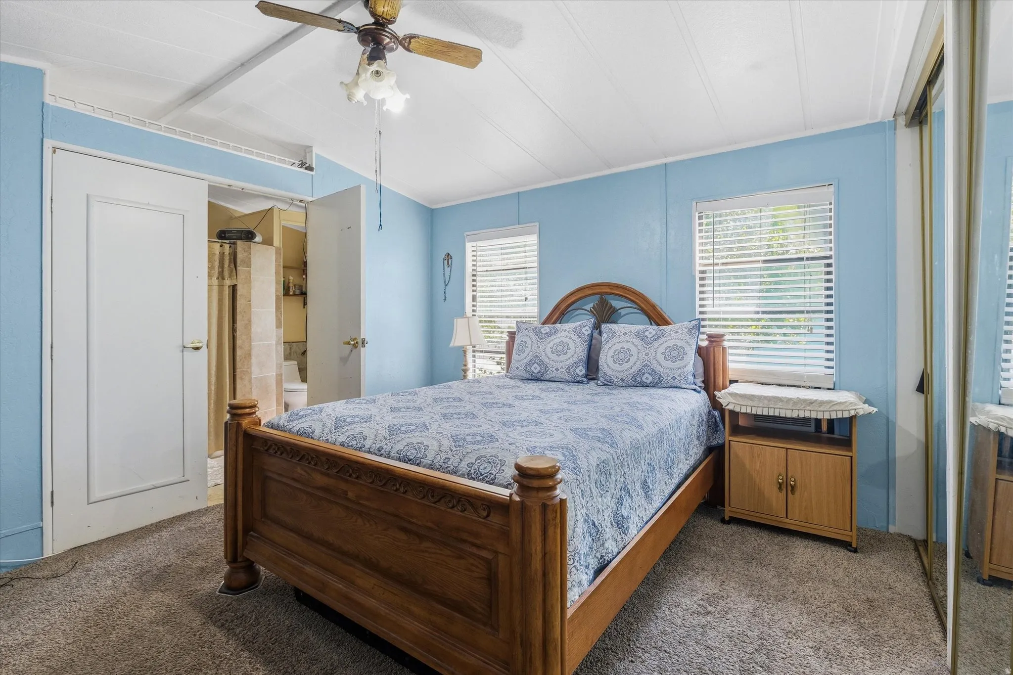 Carpeted bedroom featuring blue walls and a wood-finish ceiling fan with integrated lighting