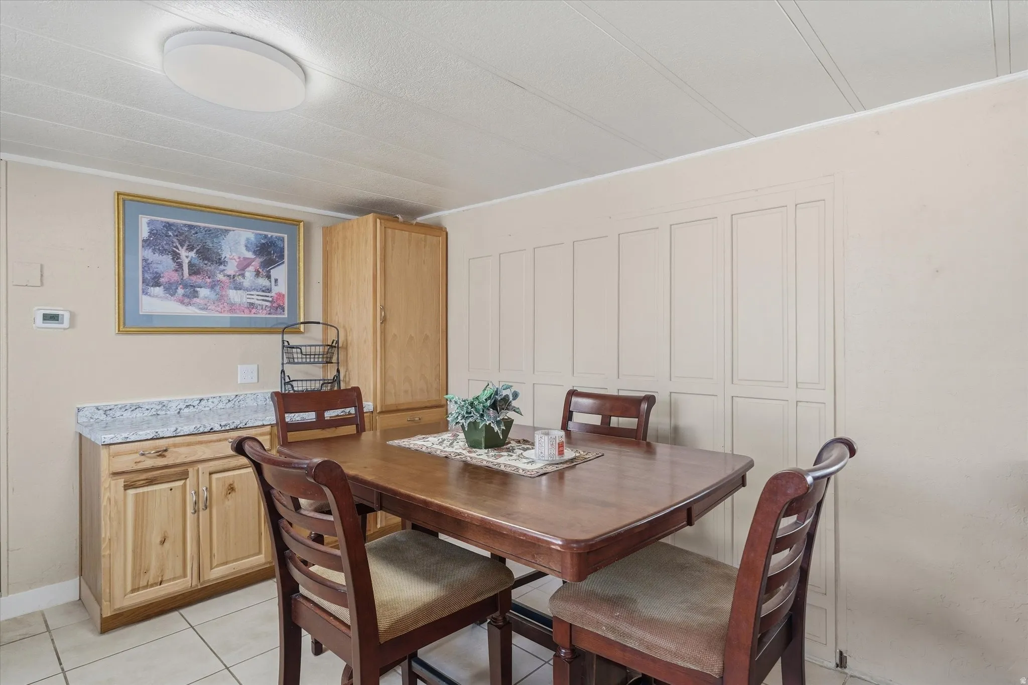 Dining area featuring a built-in wood-finish cabinet with a granite-look countertop, a full-height pantry cabinet, and tile flooring