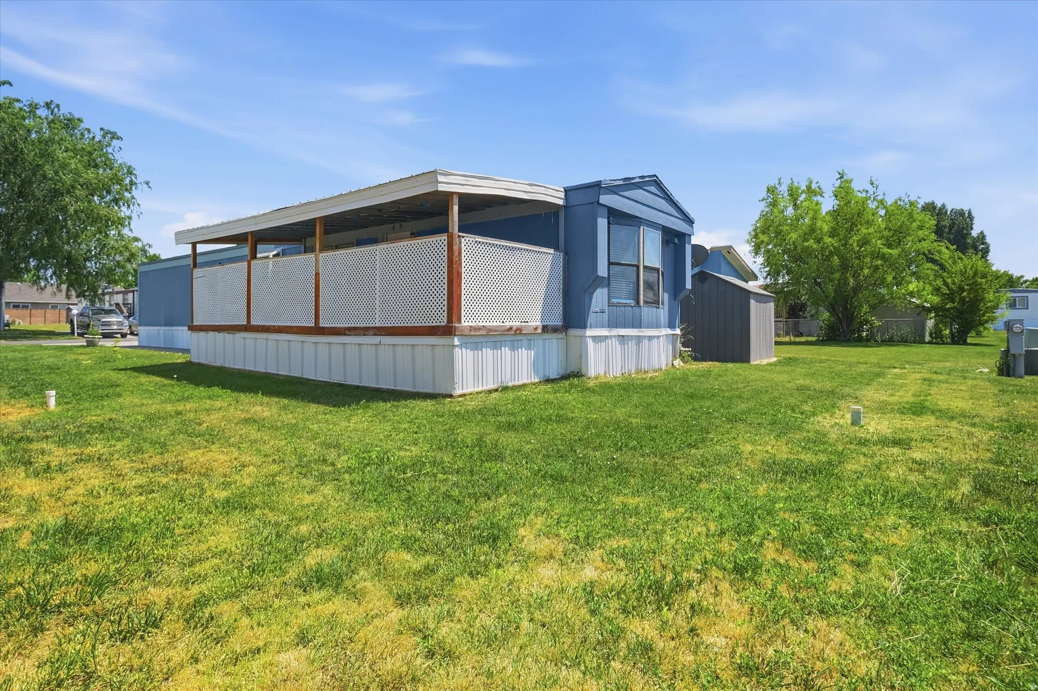 Expansive grassy yard area featuring a covered porch with white lattice railing