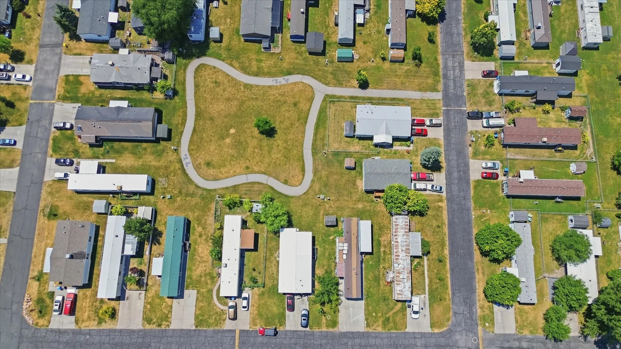 Aerial perspective showcasing a residential community with paved roads, individual driveways, and expansive grassy areas