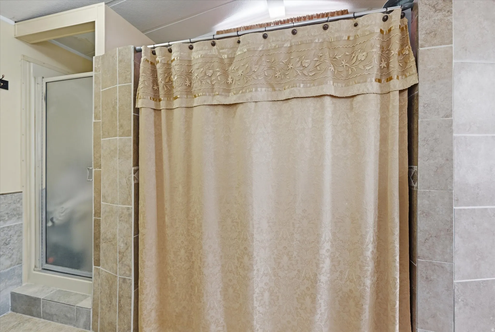 Bathroom featuring a tiled shower enclosure and a separate shower stall with a frosted glass door