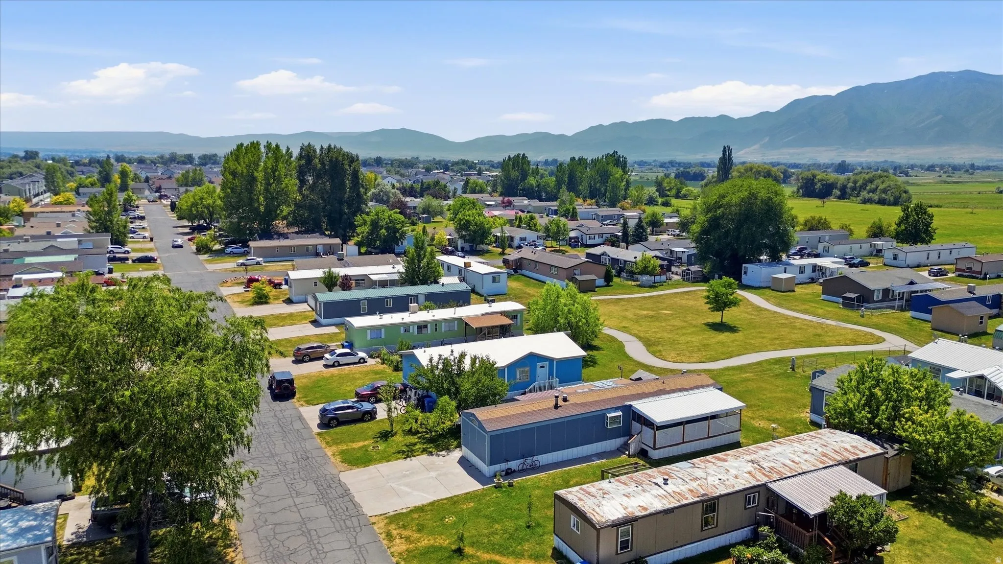 Community featuring paved streets, mature trees, open green spaces, and mountain backdrops