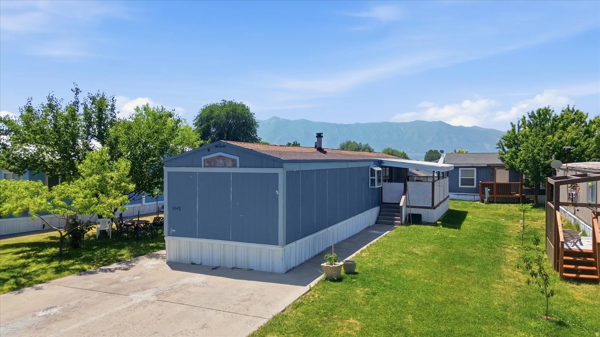 Single-story residence featuring blue siding with white skirting, a covered porch, and a gravel driveway