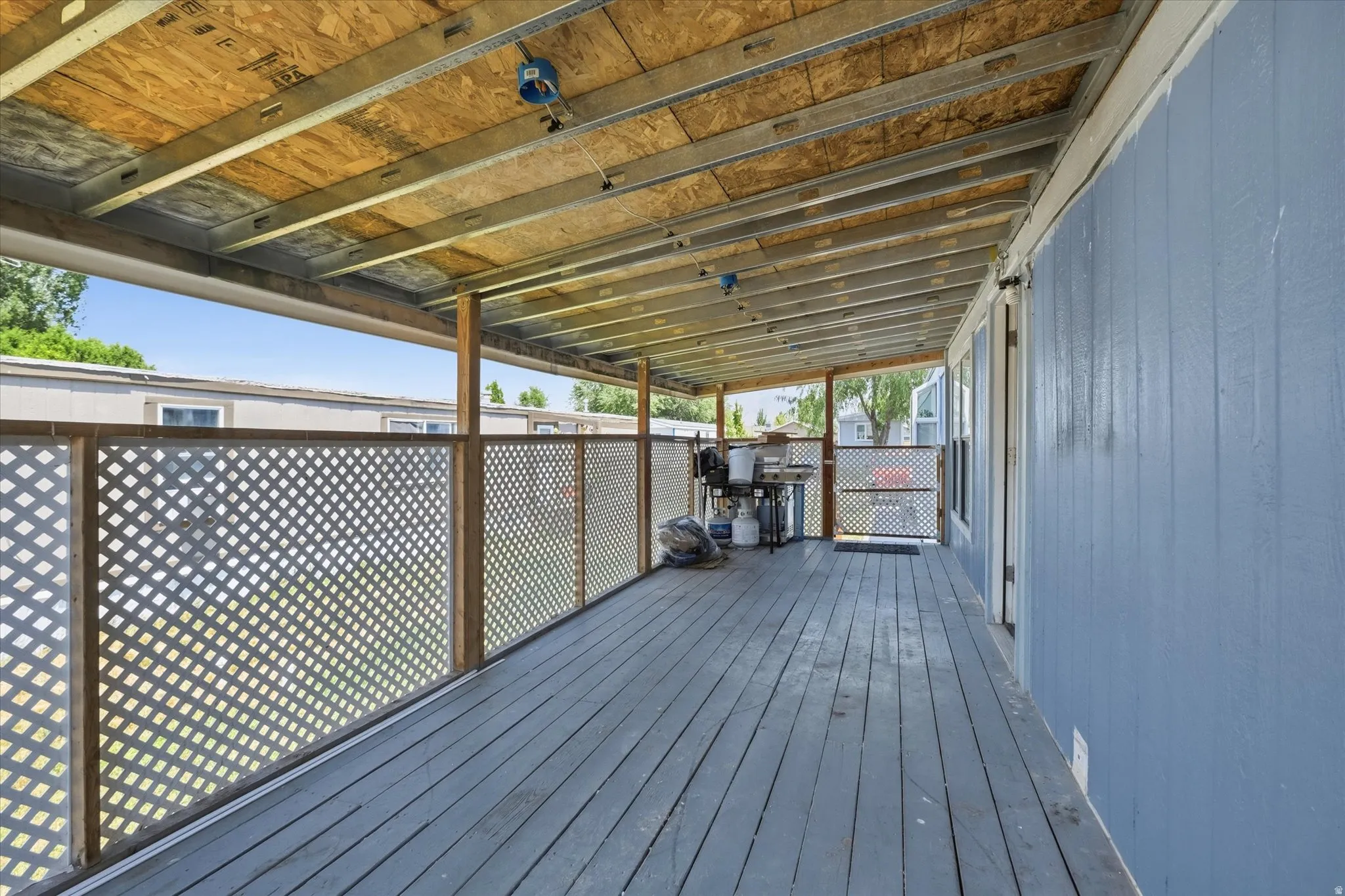 Covered outdoor deck featuring wood-finish flooring and lattice privacy screening