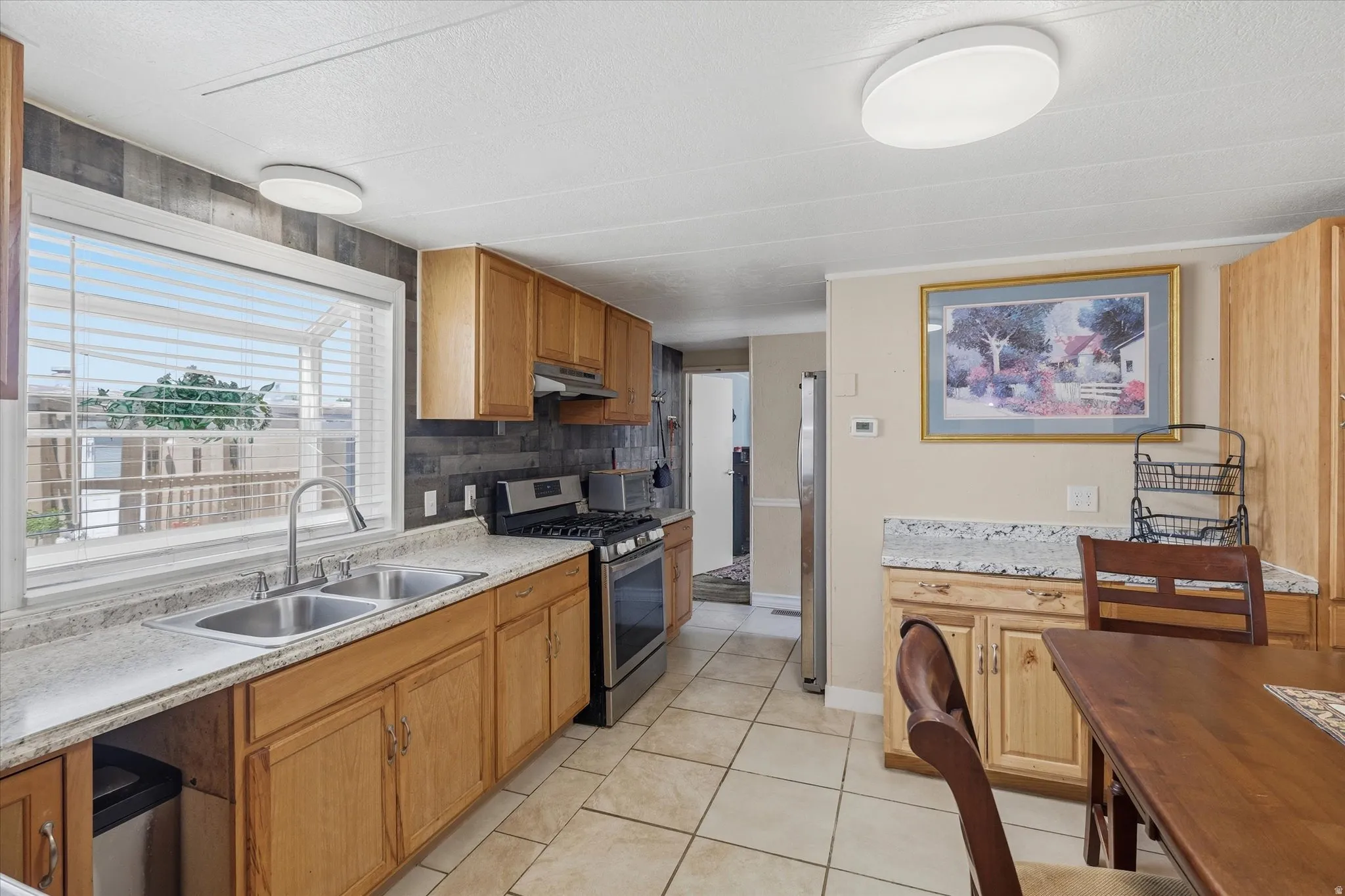 Kitchen featuring light wood cabinetry, light-toned countertops, and a stainless steel double basin sink