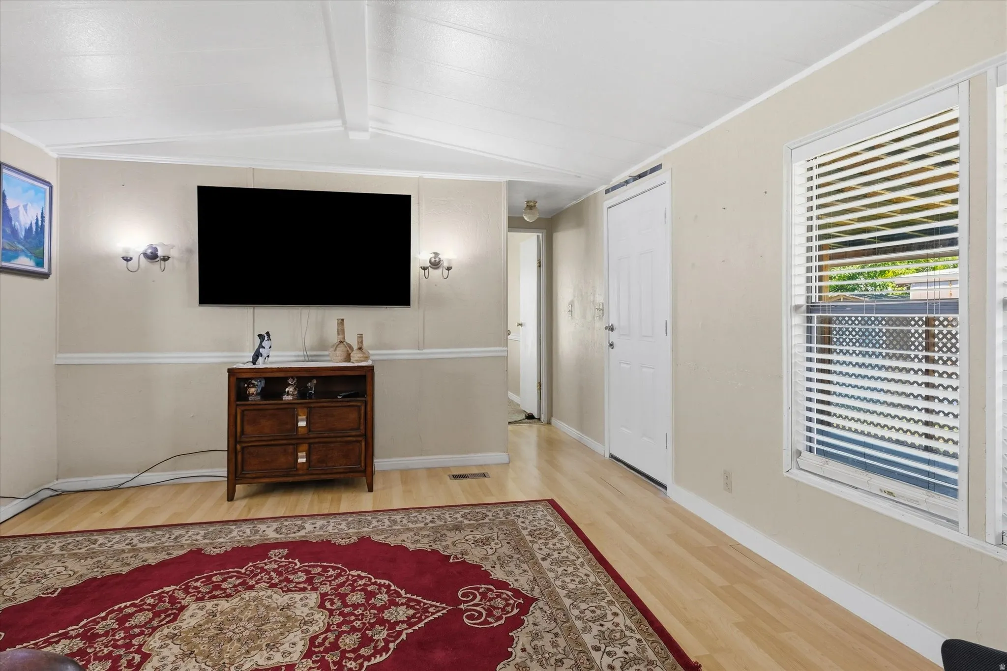 Spacious living area featuring light-toned wood-finish flooring, neutral wall tones, and white trim