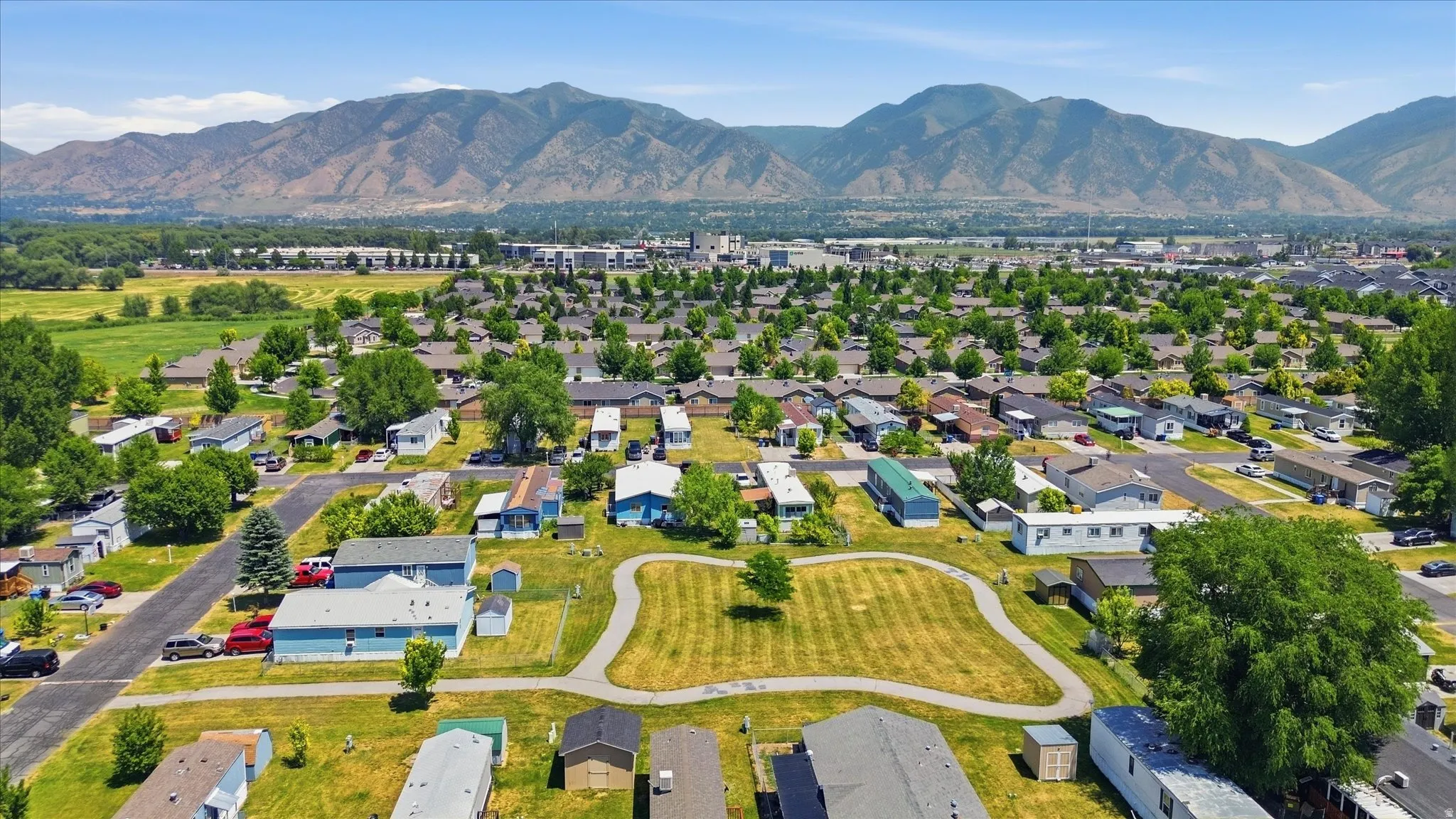 Expansive residential community featuring mature trees, paved streets, and a central green space with a walking path